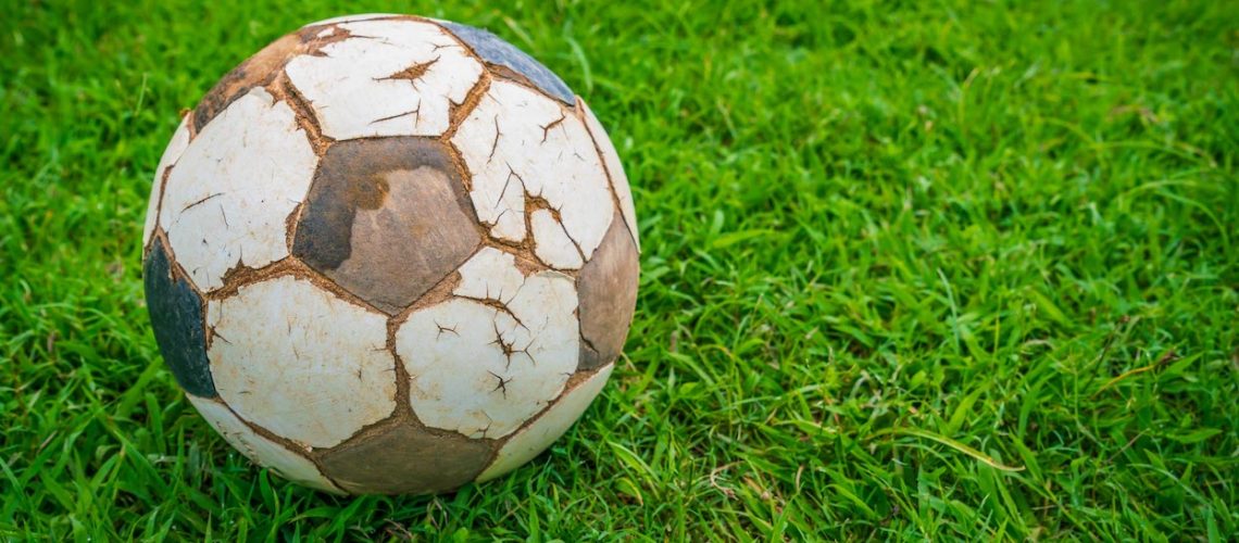 Old soccer ball on fresh spring green grass